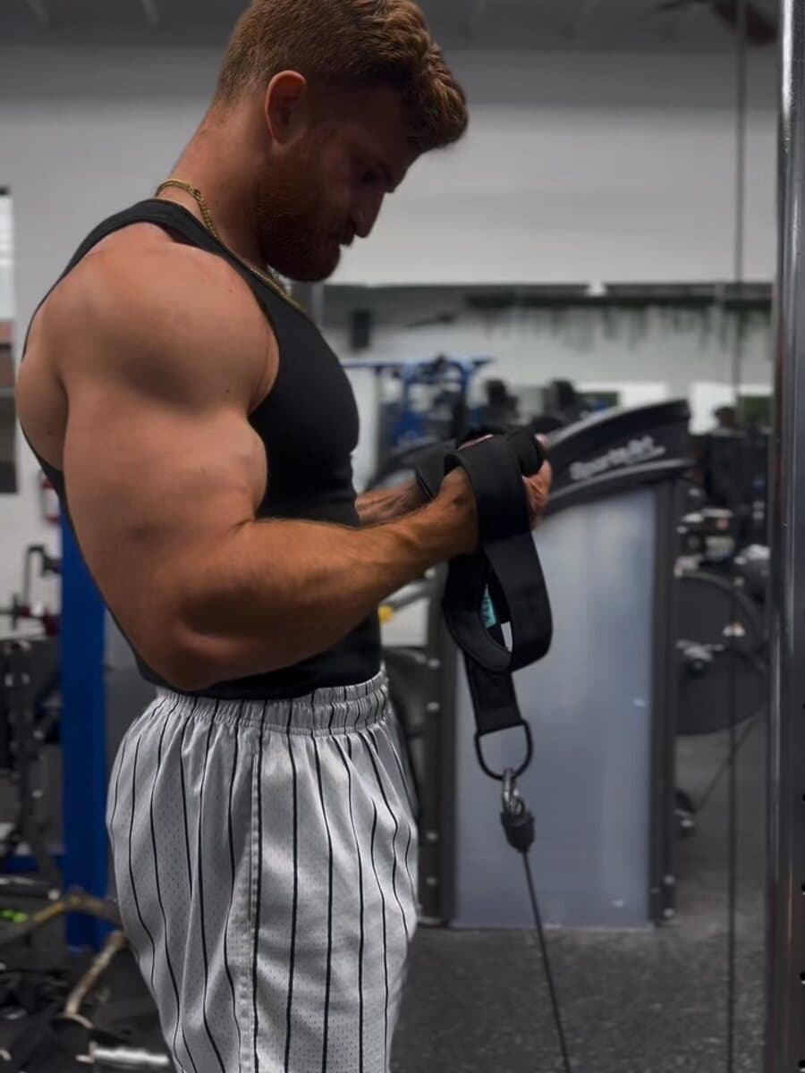 Brad Hills mid set on a cable machine in a dark commercial gym